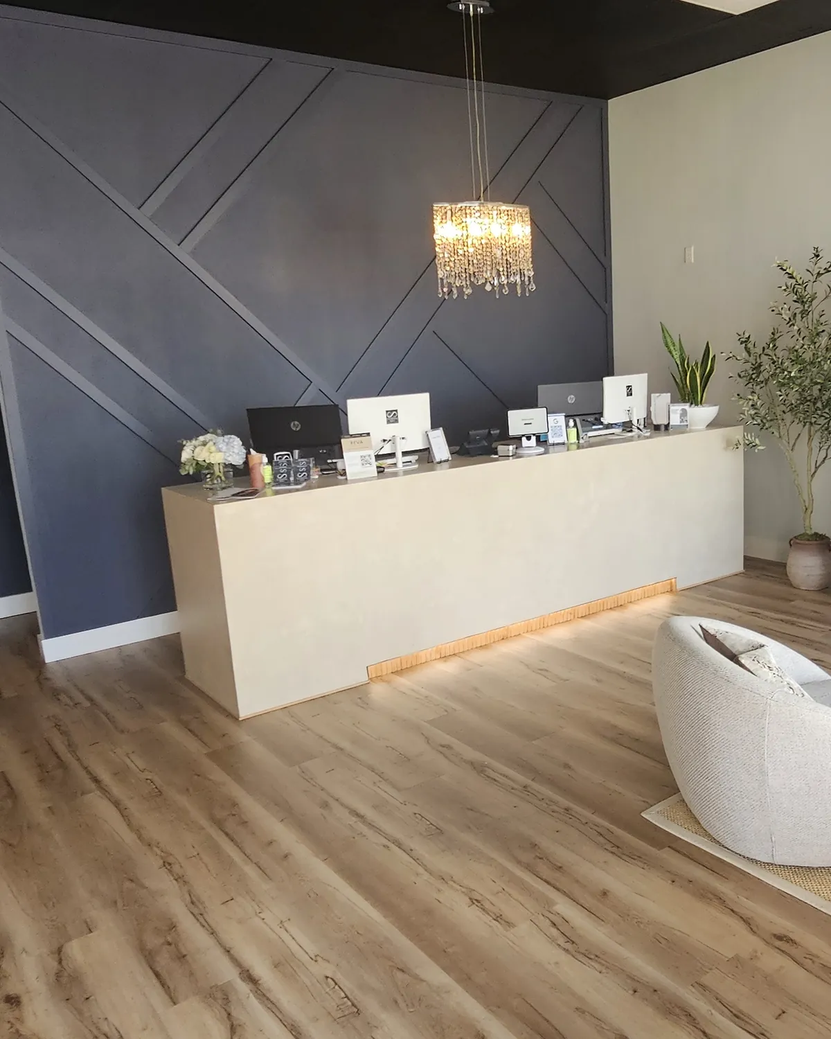 Front desk at Eternal MedSpa Sarasota: a cream counter under a crystal chandelier against a navy accent wall, used for VIP memberships in Sarasota and Venice