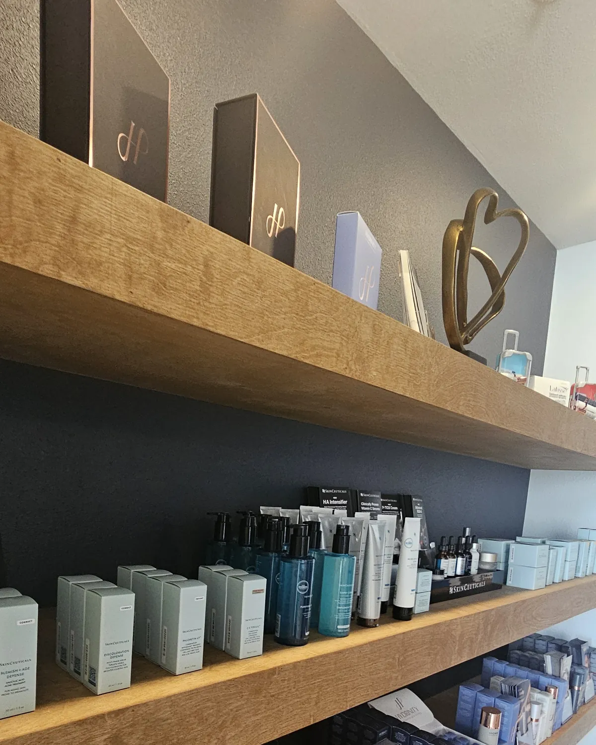 Skincare shelves at Eternal MedSpa Sarasota: SkinCeuticals serums and boxes on oak shelves against a navy wall