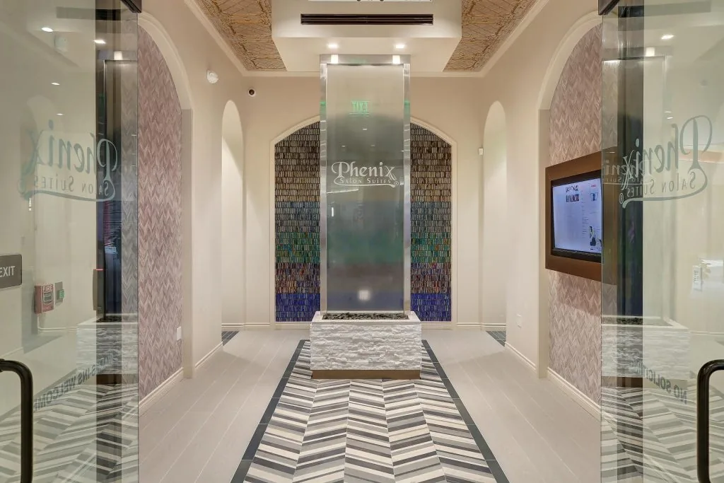 Main entrance hall of Phenix Salon Suites, with a water wall ahead and a directory screen on the right